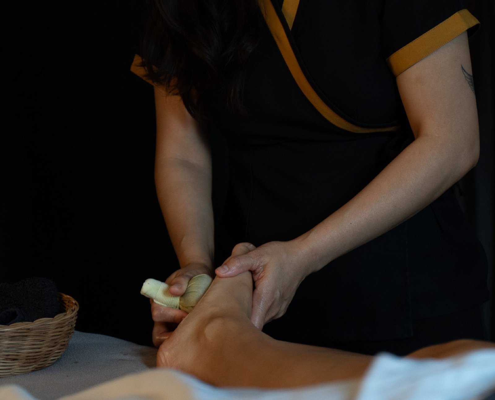 Sense therapist using a warm herbal compress during a Thai Feet Recovery massage